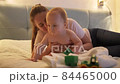 Cute baby boy crawling away from mother on bed at night. Concept of parenting, child development and family having time together. 84465000