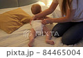 Mother changing messy used diapers to her baby son at night. Concept of children hygiene, healthcare and family care at home 84465004