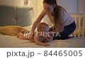Caring mother putting on diapers on her little baby son crawling on bed at night. Concept of children hygiene, healthcare and family care at home 84465005
