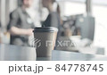 A glass of hot coffee is on the bar. Baristo in the background make coffee. Blurred background. 84778745