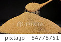 Cane sugar unrefined. A heap of sugar is mixed with a wooden spoon. 84778751
