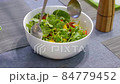Woman mixing delicious superfood salad ingredients with spoons in kitchen 84779452