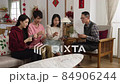 asian family taking turns discarding card on table while playing poker during spring festival at home. excited mother talking with gestures. chinese text translation: spring and congratulations 84906244