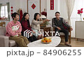 asian family laughing and pointing with finger enjoying watching tv together in living room on chinese lunar new year holiday. word at background translation: spring and congratulation 84906255