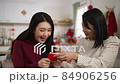 closeup of surprised daughter giving her mother a hug with smiling face while receiving red envelope lucky money during spring festival at home 84906256