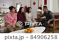 family chatting on sofa in the living room during spring festival. everyone laughing as son raising hand asking silly question. chinese words translation: spring and congratulation 84906258