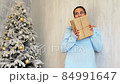beautiful pregnant woman with gifts at the Christmas tree new year 84991647