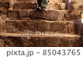 An unknown person goes down the stone stairs in an ancient fortress. 85043765