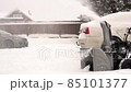 Villager removes snow with snowblower in yard at snowfall in slow motion 85101377