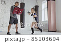 Cute girl learns kickboxing techniques in the gym with an experienced trainer 85103694