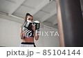 white female athlete boxing the punching bag in urban industrial gym 85104144