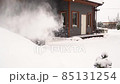 Man in village courtyard removes snow with snowblower in slow motion 85131254