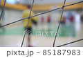 Professional volleyball players in action on grand court. Sport mesh on blurred background of competing people, indoor. Teamwork concept, selective focus 85187983