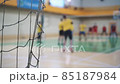 Professional volleyball players in action on grand court. Sport mesh on blurred background of competing people, indoor. Teamwork concept, selective focus 85187984