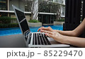 Close up hands typewriting on laptop keyboard near swimming pool in slow motion. 85229470