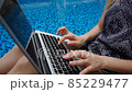Close up laptop and hands typing message with swimming pool background in slow motion. 85229477