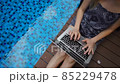 Close up girl lying near blue swimming pool and chatting by laptop in slow motion. 85229478