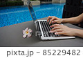Сlose up hands chatting on laptop keyboard with swimming pool in slow motion. 85229482