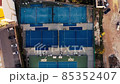 Tennis court aerial view. Slow, top down drone flight over blue outdoor fields with players at practice. Tennis court aerial view. Slow, top down drone flight over blue outdoor fields with players at practice. 85352407