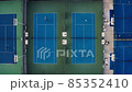 Tennis court aerial view. Slow, top down drone flight over blue outdoor fields with players at practice. Tennis court aerial view. Slow, top down drone flight over blue outdoor fields with players at practice. 85352410