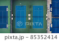 Tennis court aerial view. Slow, top down drone flight over blue outdoor fields with players at practice. Tennis court aerial view. Slow, top down drone flight over blue outdoor fields with players at practice. 85352414