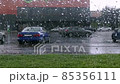 a cyclist in heavy rain passes from left to right outside the window with water droplets  85356111