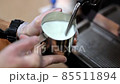 Crop barista steaming milk for coffee 85511894