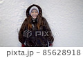 Smiling woman lying on the snow in winter and throwing white snow on her, top view 85628918