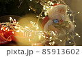 A Santa Claus toy or doll stands on a Christmas tree next to gifts. 85913602