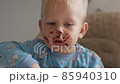 A cute little boy eats chocolate with pleasure smiling and laughing close-up 85940310