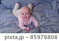 Caucasian baby lying on bed laughing. 85978808