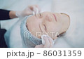 Dermatologist doctor wipes the face of the patient with a disinfecting compound in order to do the cosmetic procedure 86031359