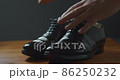 A man pulling a wooden shoe tree out of black business shoes 86250232
