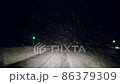 吹雪のなか夜の高速道路を走る車から見た冬の風景 86379309