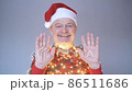 Senior bald man in christmas hat and garland waving hand welcoming friends. 86511686