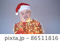 Senior sad man in red christmas hat wrapped in garland. 86511816