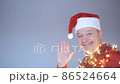 Senior bald man in christmas hat and garland waving hand welcoming friends. 86524664