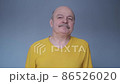 Tired senior man having pain or neck ache. Guy in casual yellow t-shirt takes break. 86526020