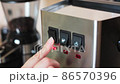 a person's hand presses a finger on the button for turning on an espresso coffee machine. close-up of household appliances made of steel. 86570396