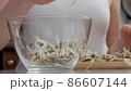 Close-up of a woman's hands dividing fresh mushrooms into fibers and throwing them into dishes 86607144