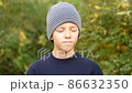 serious boy in striped hat standing in park looks at camera and nods his head in agreement 86632350