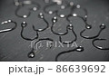 Fish hooks made of dark metal are scattered on a gray table in close-up. Background in blur. 86639692