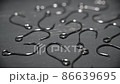 Fish hooks in close-up are scattered on a dark gray table. Background in blur. 86639695