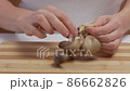 Close-up of female hands on a chopping board separating fresh mushrooms into fibers 86662826