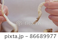 Close-up of female hands on a chopping board separating fresh mushrooms into fibers 86689977