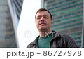 Millennial guy looking at camera, smiling and waving hello greeting gesture standing at city street 86727978