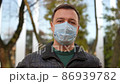 Millennial man takes off his medical mask outdoors and throws it back over his shoulder 86939782