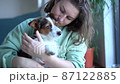 Smiling caucasian woman kissing and cuddling her pet dog sitting on floor at home. lifestyle, pet, companionship and animal friendship concept 87122885
