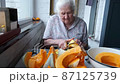 Old woman cuts and pills yellow pumpkin, cooking pumpkin soup, retirement life, selective focus 87125739