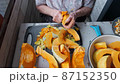 Old woman cuts and pills yellow pumpkin, cooking pumpkin soup, retirement life, selective focus 87152350